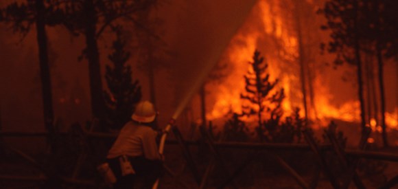 A firefighter uses a hose to quell flames near the Norris Museum