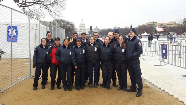 A group of teens wearing EMT uniforms stands along the National Mall with the capital in the background.