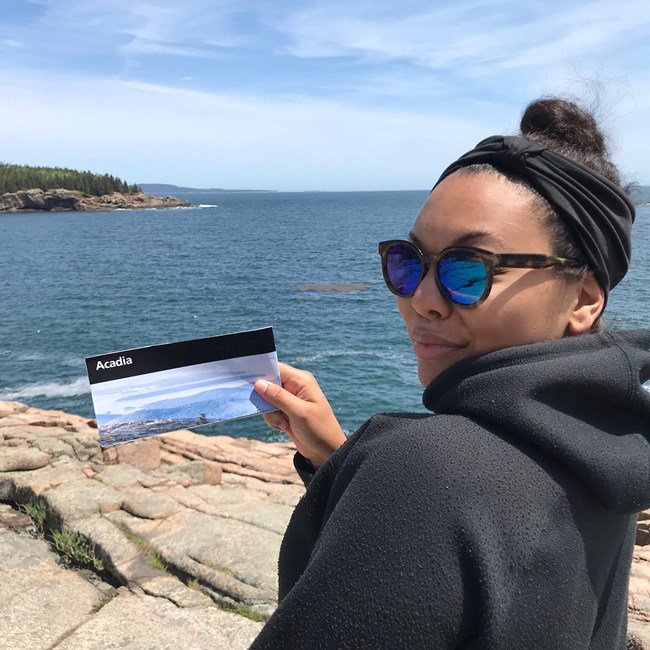Woman holding a park brochure stands along ocean coastline Woman holding a park brochure stands along ocean coastline