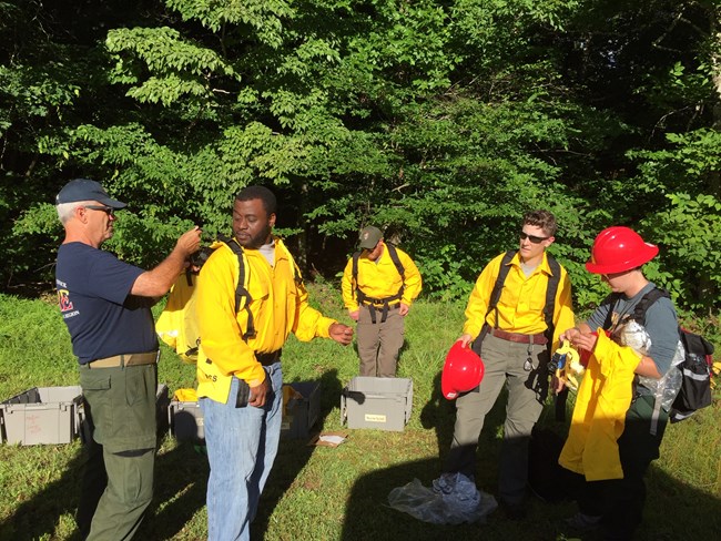 Firefighter trainees practice putting on wildland firefighting gear.