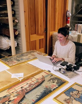 Conservator Angela Campbell sits at a computer, surrounded by Japanese prints. A conservator sits at a computer, surrounded by Japanese prints.