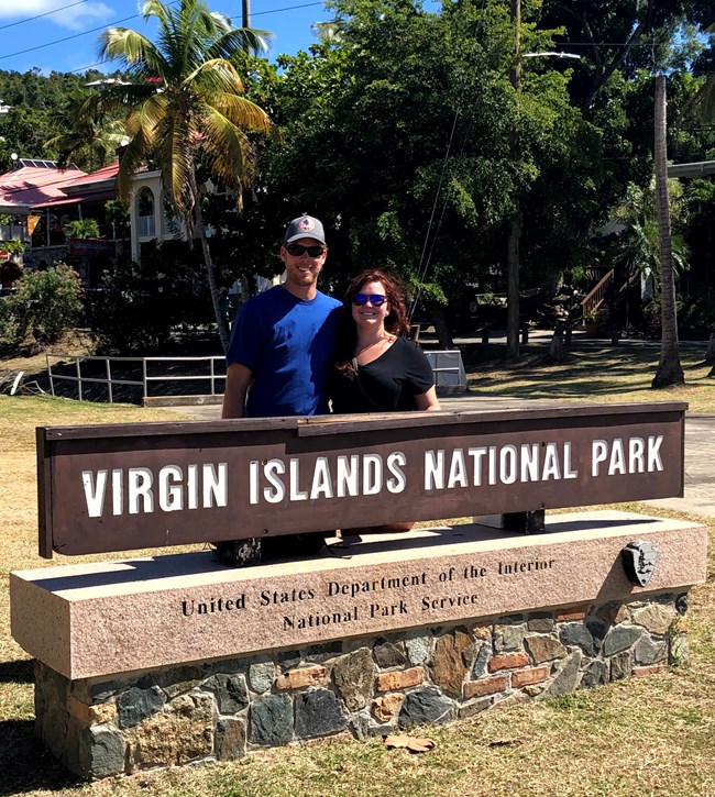 A couple pose behind the Virgin Islands National Park wooden sign.