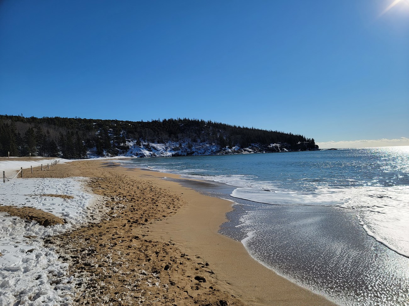 Snow Covered Sand Beach snow covers sand beach with ocean tide keeping some sand clear
