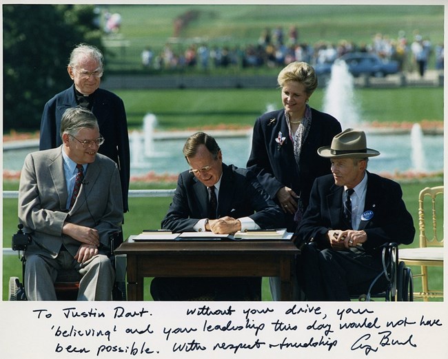 President George H.W. Bush signing the Americans with Disabilities Act. Photo inscribed to Justin Dart, Jr., 1990.