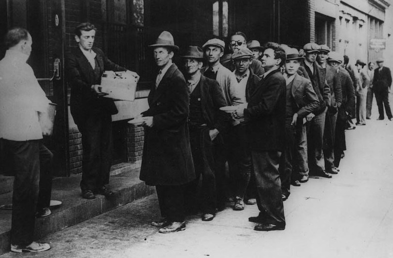 Many men stand in line along the street.