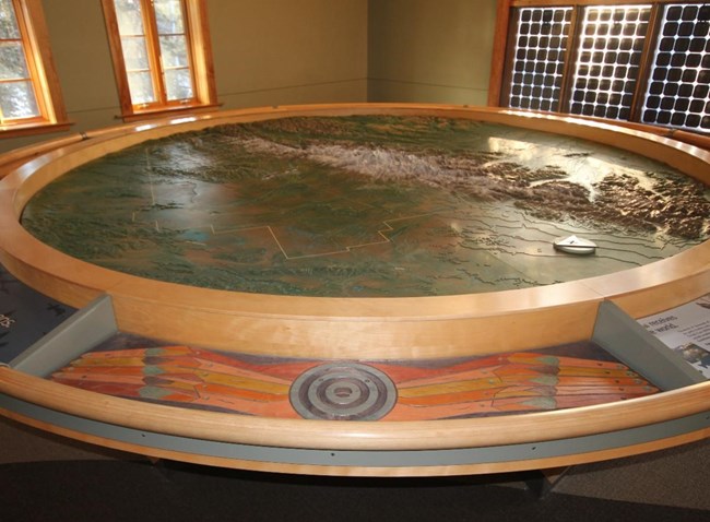 a large circular topographic relief map in a visitor center