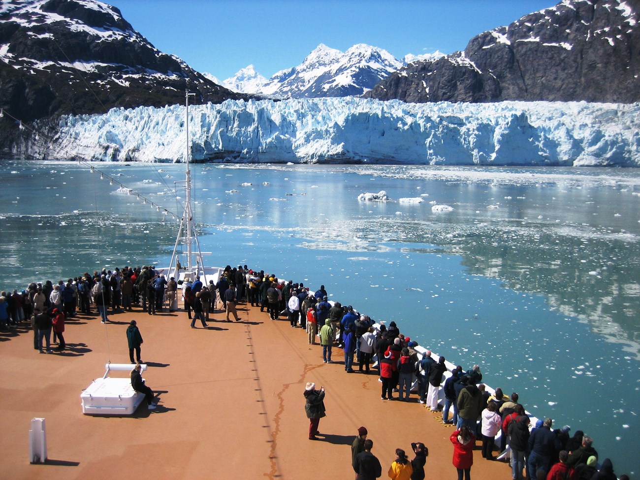 Visitors to Glacier bay national park gather at the bow of a cruise ship, overlooking the water