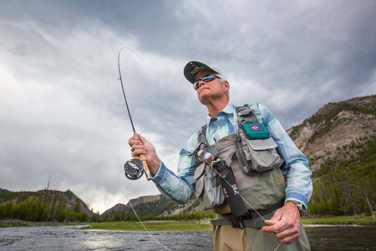 A fly fisherman stands in a river and casts his rod.