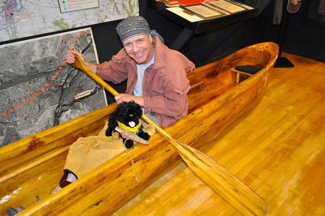 docent in dugout canoe with toy dog