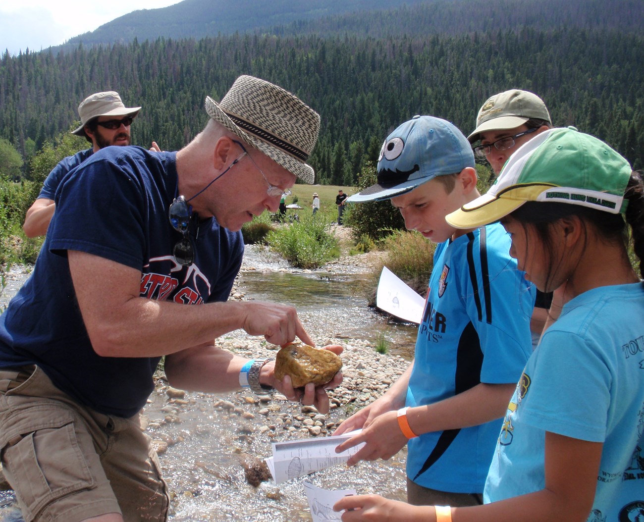 Scientist points out larvae living among river cobbles