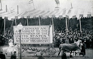 Horses pull float with banner: "We Demand an Amendment to the Constitution of the United States Enfranchising Women."