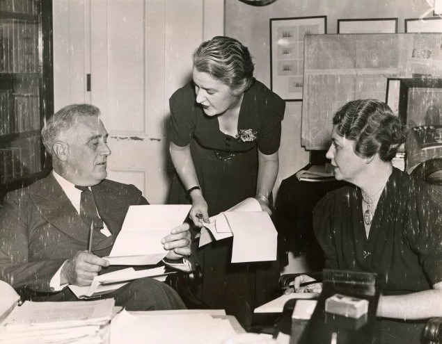 FDR Study with LeHand and Tully A man and two women work at a cluttered desk.