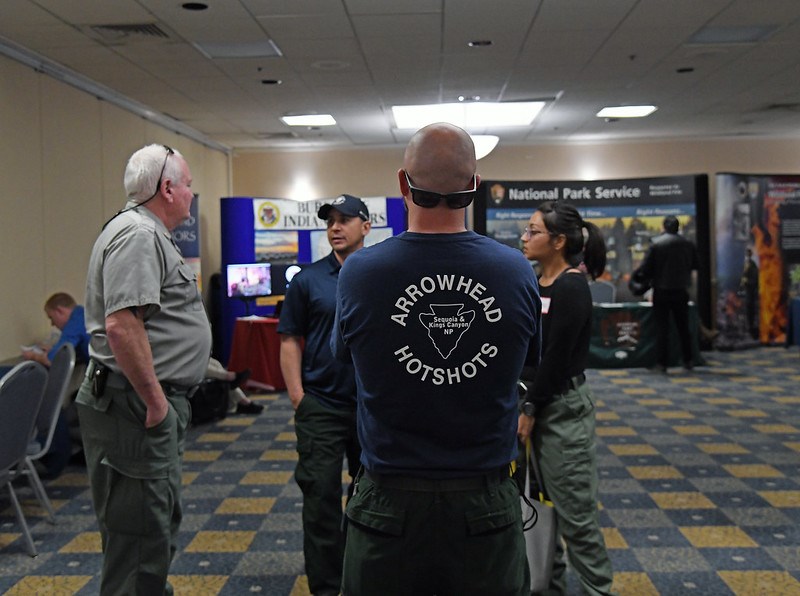 DOI_Hiring_Event_2020_ArrowheadHotshot Three employees talk with a potential candidate at a job fair.