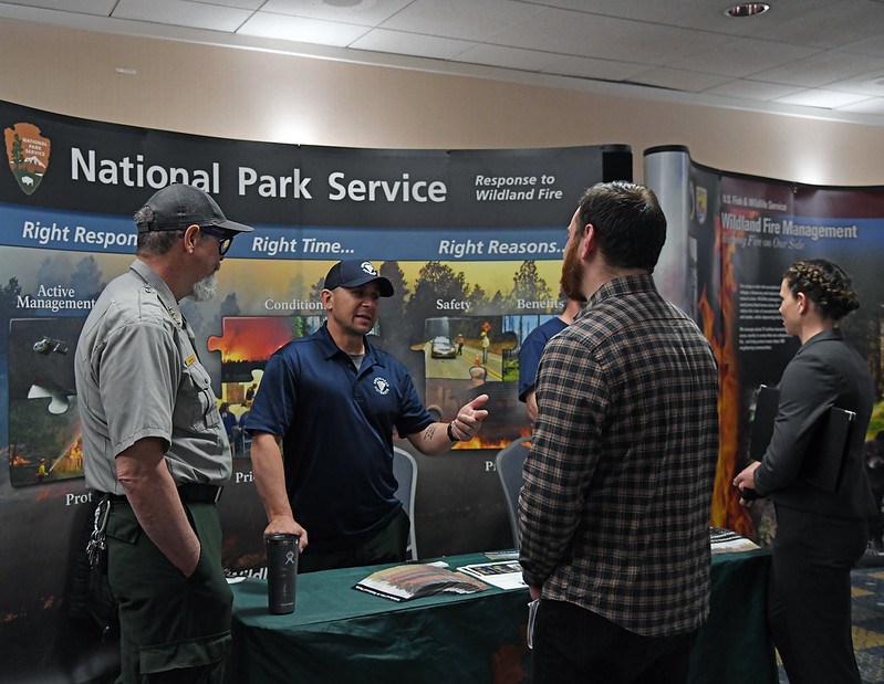 DOI_Hiring_Event_2020 National Park Service employees meet with job candidates in front of a display about the wildland fire program.