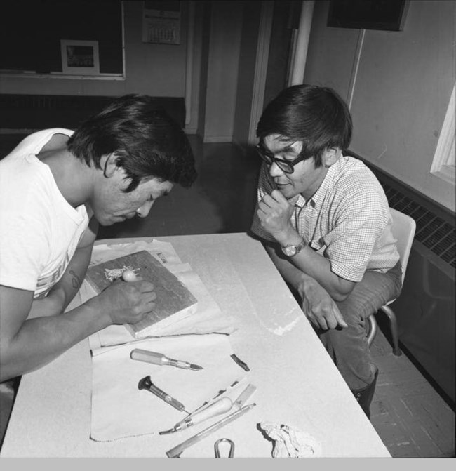 senungetuk 4 two men at a table looking at some kind of woodblock carving