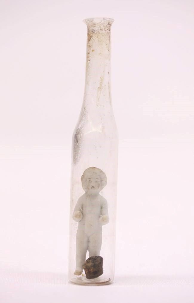 A tall glass bottle with a white ceramic figurine inside.
