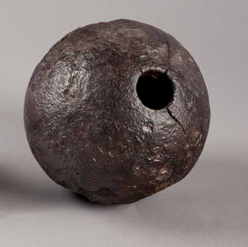 A pocked metal ball with a hole drilled in the side. It is hollow.