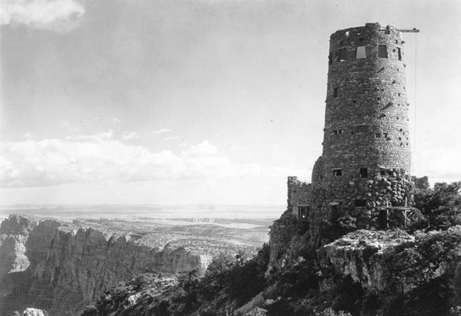 Large stone tower on cliff's edge overlooking scenic canyon view.