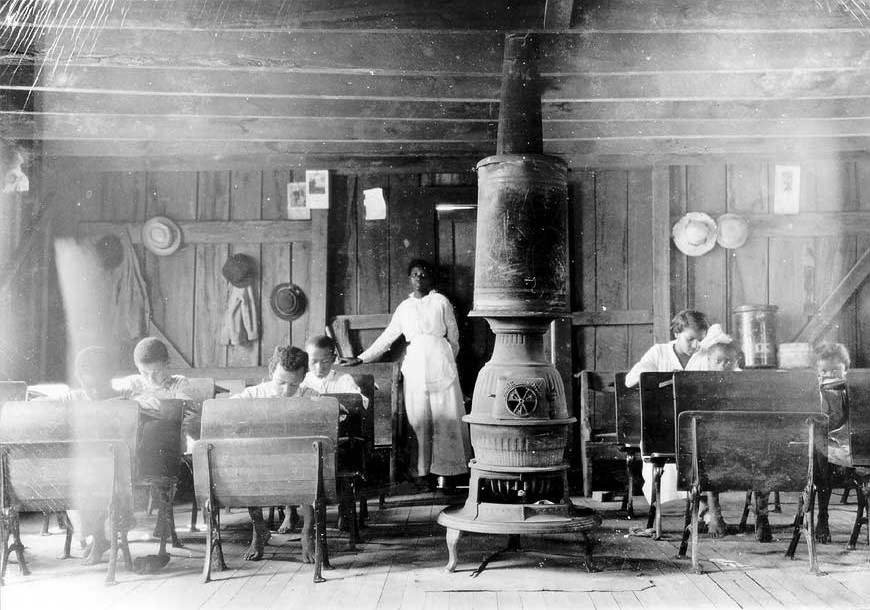 Woman and children in one room school house.