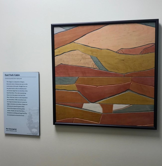 geometric artwork hanging on a wall depicting a wilderness scene in an abstract way