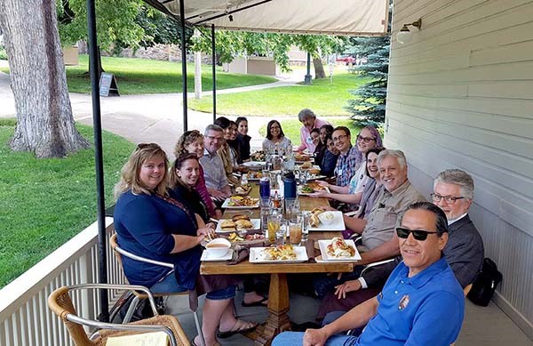 A group of smiling people sit around a table with food. A group of smiling people sit around a table with food.
