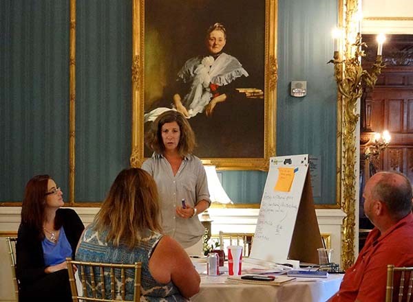People talk while sitting and standing around a table. People talk while sitting and standing around a table.