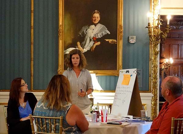 People talk while sitting and standing around a table.