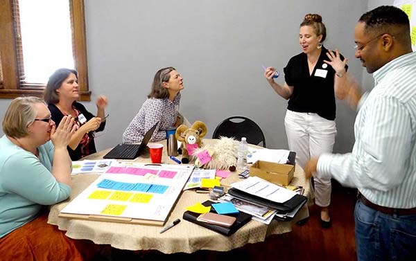 People talk while sitting and standing around a table. People talk while sitting and standing around a table.