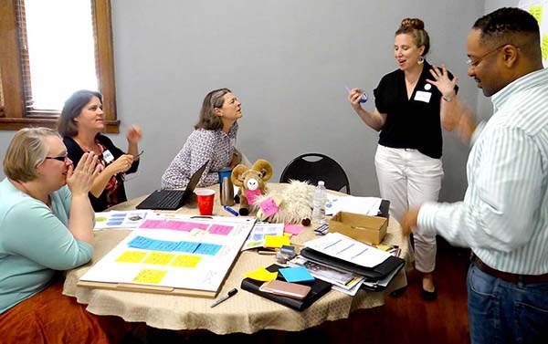 People talk while sitting and standing around a table.