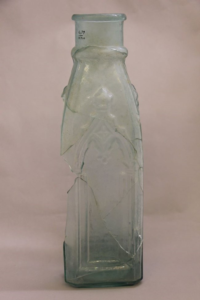 A tale cloudy glass jar with embelishments etched on it.