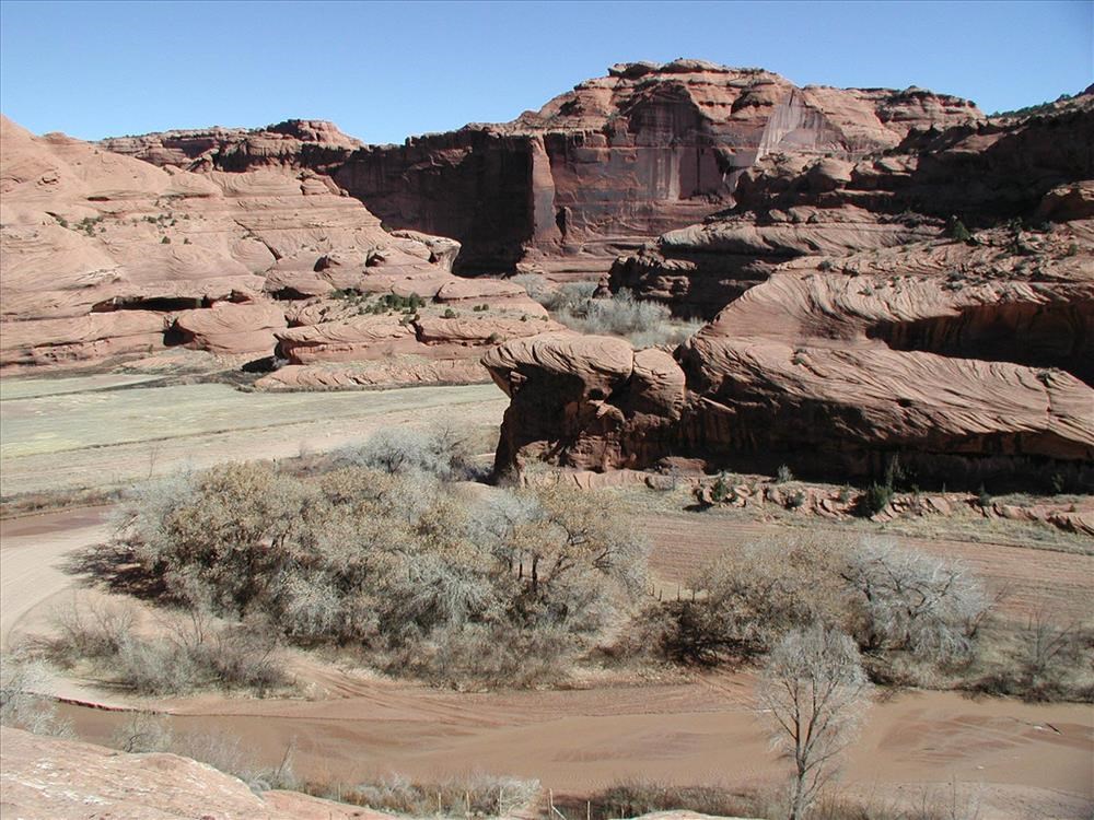 An extra wide shot of a barren, dry landscape, featuring red canyon walls and cliffs. An extra wide shot of a barren, dry landscape, featuring red canyon walls and cliffs.