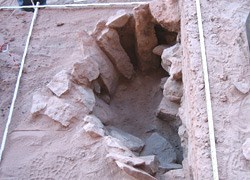 The deep, stone-lined hearth. A deep hearth in a non angular shape lined by tall stone.