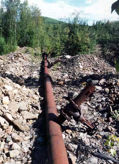 long rusty pipe running along a rocky surface in a forest long rusty pipe running along a rocky surface in a forest