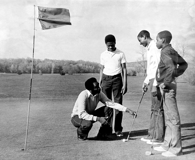 A man instructs boys to play golf