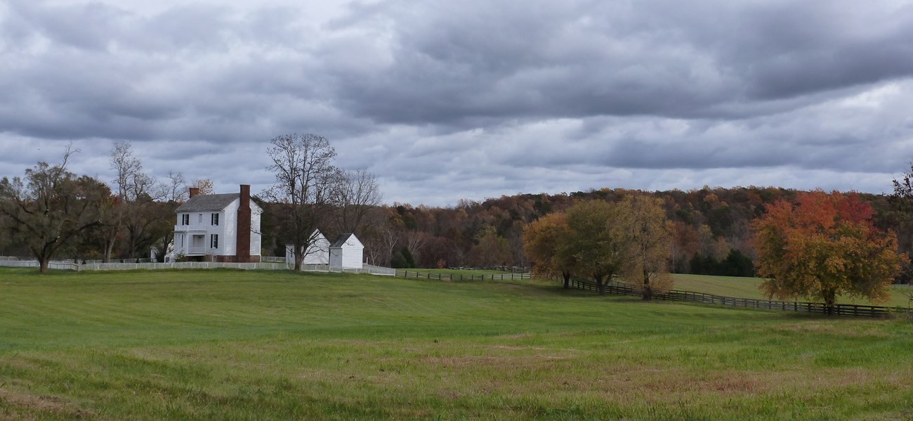Peers house as viewed from a distance across a green field with storm clouds in the background