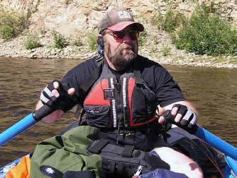 man sitting in a small raft with two oars