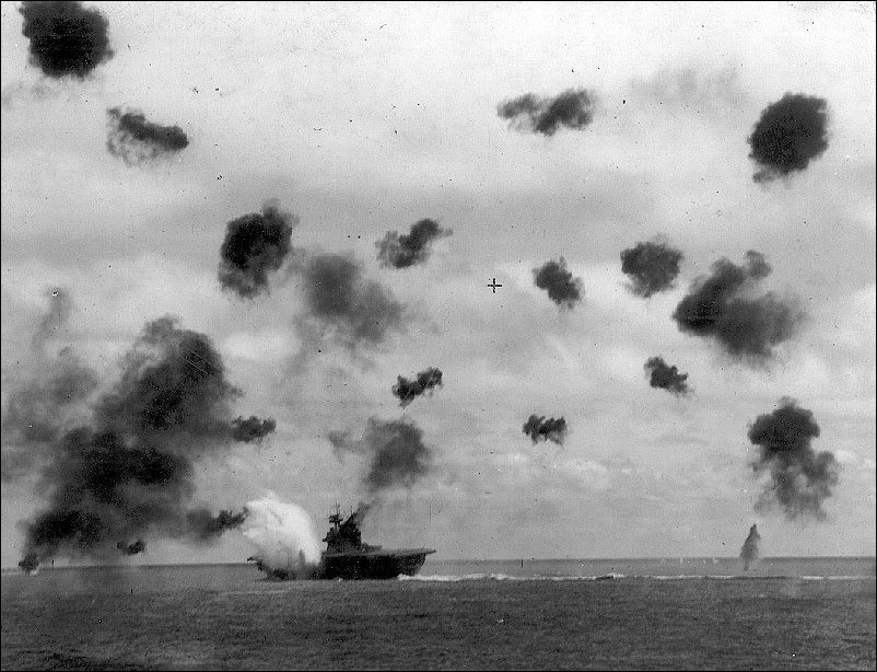 Bombs exploding over a carrier ship.