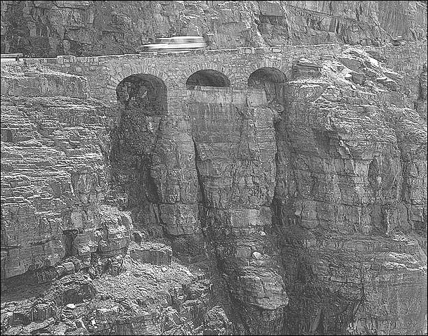 Three rock arches in the side of a mountain.