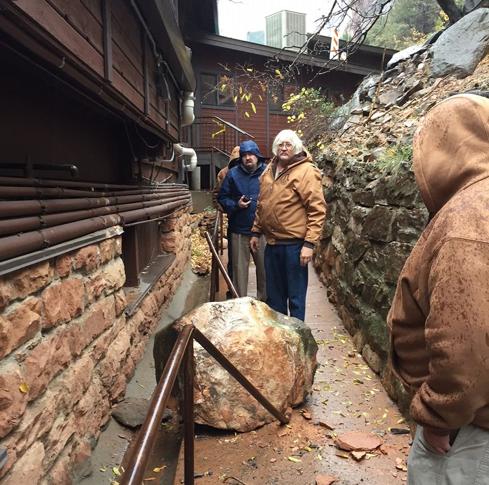 large boulder next to Zion lodge with facility men standing by it