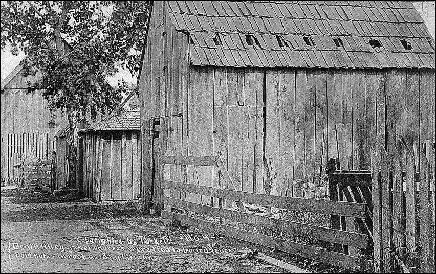 Alley-way with wooden fencing and wooden building lining the street. (Kansas State Historical Society)