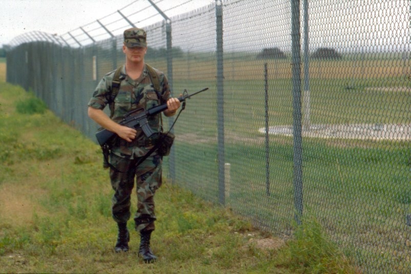 A Security Policeman patrolling the fence line at a Launch Control Facility A uniformed airman with a weapon patrols a fence-line