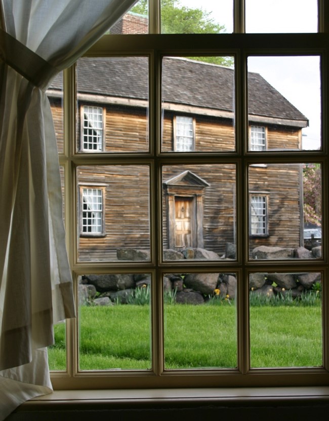 Viewing looking out a window at a two-story wooden house