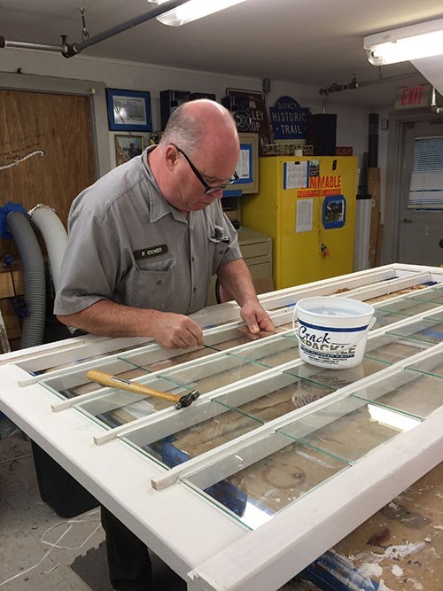 ADAM Glass Replacement NPS staff replacing a window pane on a window laying on a worktable