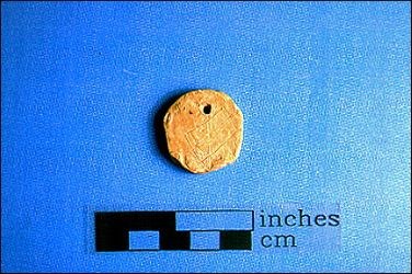 This pendant is a flattened bullet, shaped and drilled and probably worn as a makeshift dogtag, or maybe used as a favorite poker chip which never made it to the next game. This pendant is a flattened bullet, shaped and drilled and probably worn as a makeshift dogtag, or maybe used as a favorite poker chip which never made it to the next game.