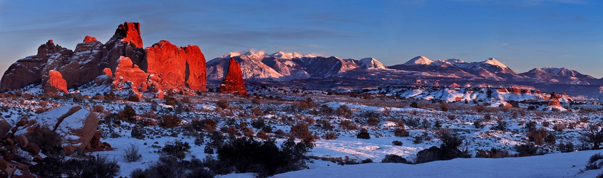 Lighting glow over snow-covered desert and rock formations