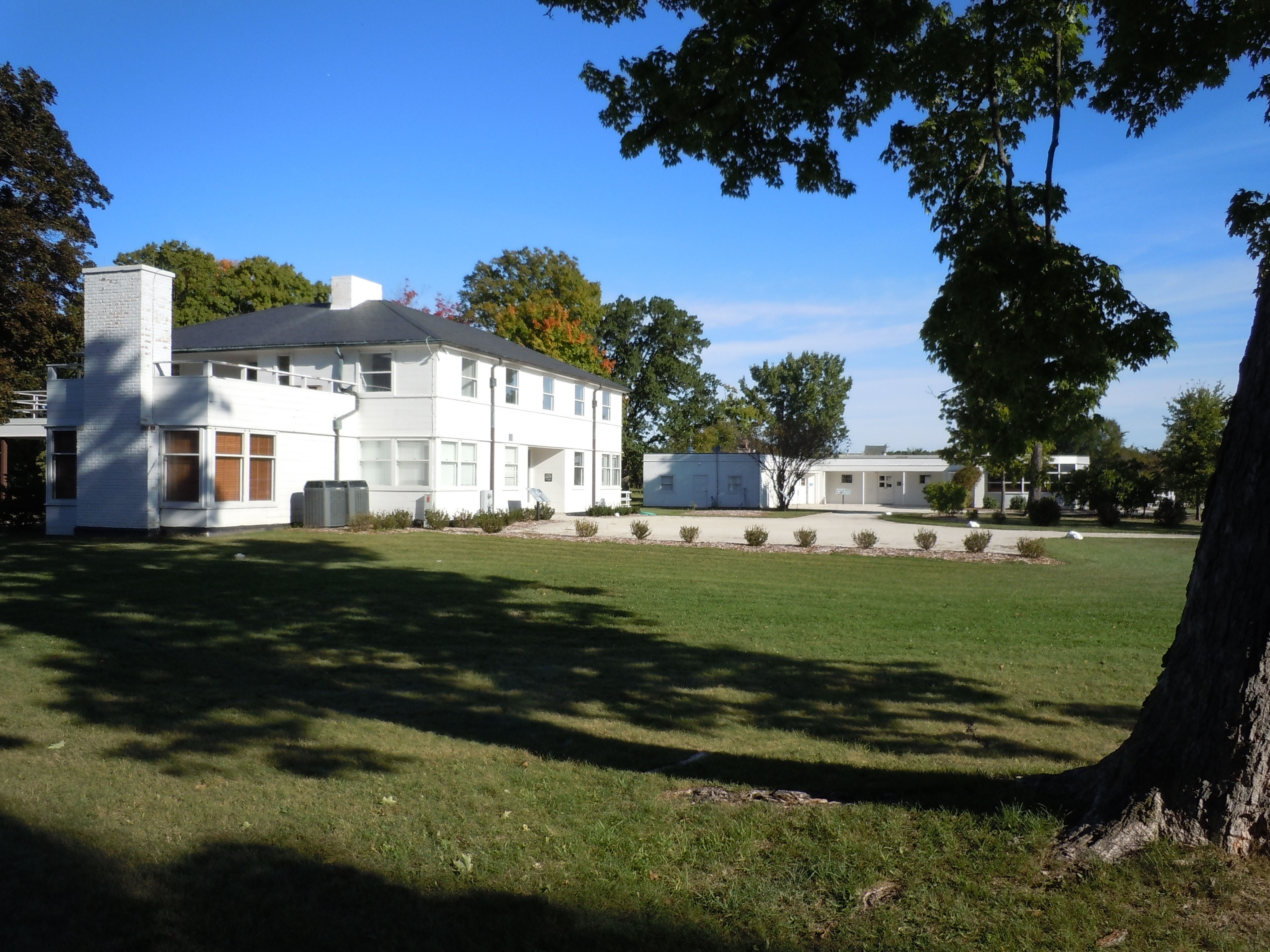 Two-story white house with a green lawn and trees.