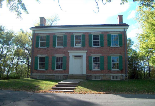 Two-story brick house with green shutters.