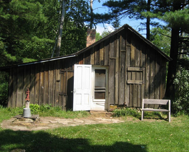 Small. wooden building near trees.