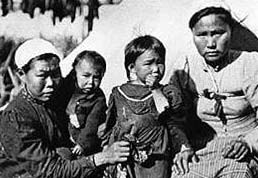 Four Alutiiq women, two adults and two children, sit together in this historic photo. Four Alutiiq women, two adults and two children, sit together in this historic photo.
