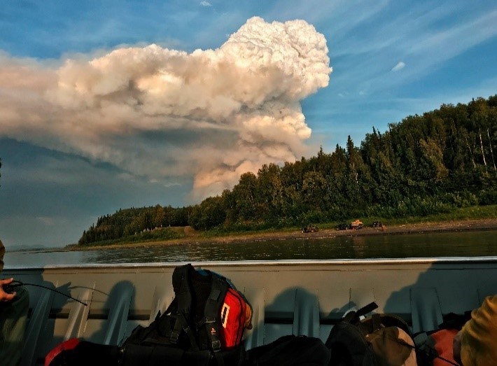 Andrew Creek Fire from Yukon River A large plume of smoke rises in an anvil-shaped cloud above the tree line on the Yukon River.